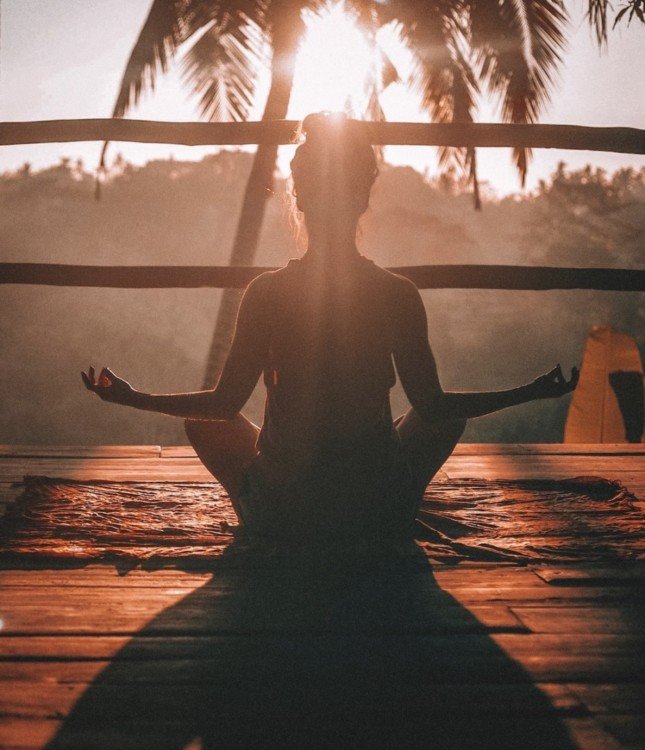 Femme en position du lotus au coucher du soleil